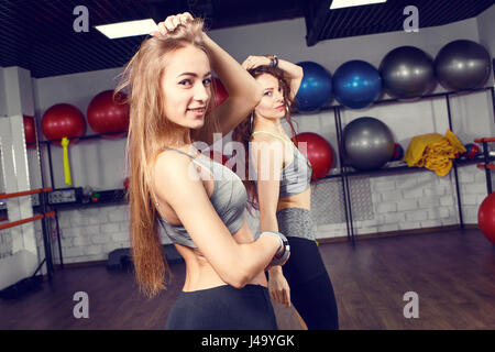 Two athletic girls training in fitness center. Smiling fitness women dancing exercises in gym Stock Photo