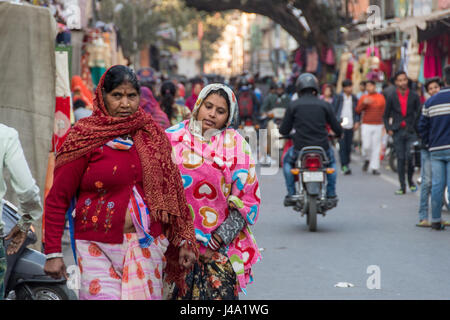 Indian women walking down the street carrying produce in basket on head ...