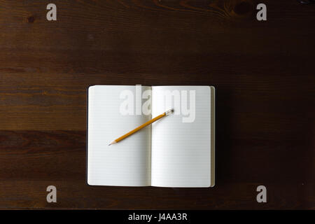 A blank notebook and pencil on a wood table, with copy space. Stock Photo