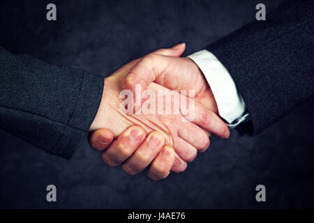 Joint enterprise handshake over business agreement, male and female businesspeople shaking hands after forming a strategic partnership Stock Photo