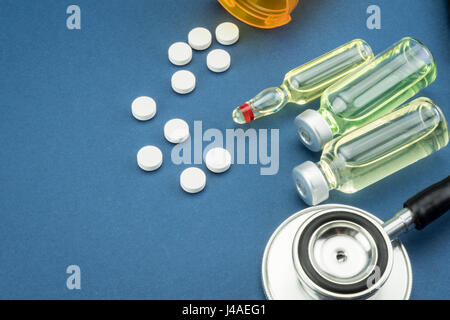 stethoscope, pills, vials in medical room on blue background Stock Photo