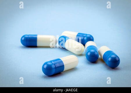 Many medicines blue and white capsules on blue background Stock Photo