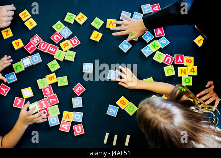 Kindergarten kids playing wooden alphabets letters vocabulary game Stock Photo