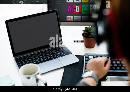 Laptop Screen Showing Black Desktop on Whtie Table beside Working Man Stock Photo