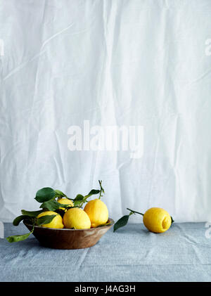 Bowl of fresh lemons in bowl on tablecloth Stock Photo