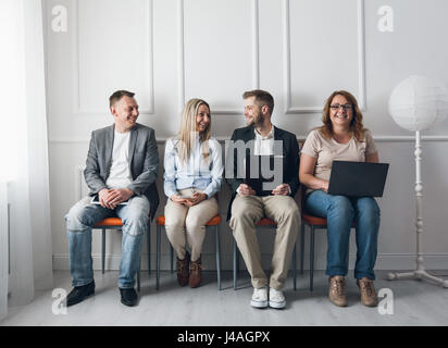 Group of young creative people sitting on chairs in waiting room Stock Photo