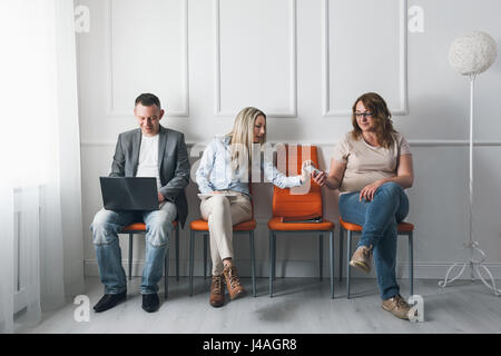 Group of young creative people sitting on chairs in waiting room Stock Photo