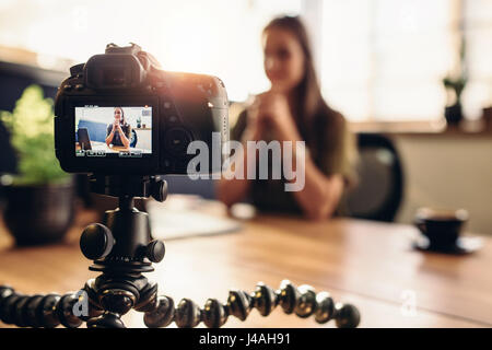 Female vlogger recording content for her video blog. Young woman in focus on digital camera screen. Stock Photo