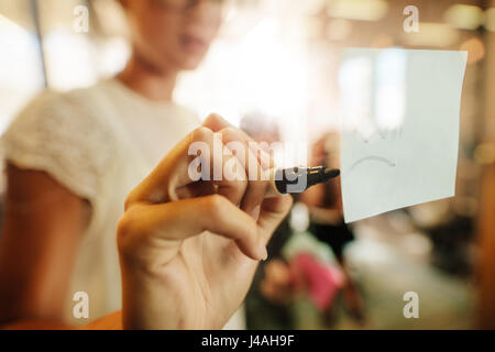 businesswoman writing with a maker pen on white card in front of her ...