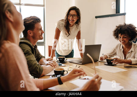 Group of multi ethnic executives discussing during a meeting. Business man and woman sitting around table at office and smiling. Stock Photo