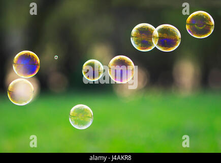 beautiful festive background with iridescent rainbow transparent soap bubbles on green grass Stock Photo