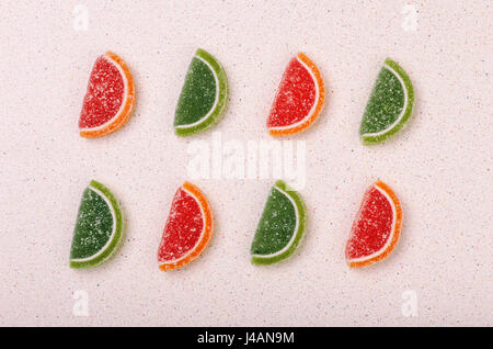 Still life of marmalade slices of citrus fruit lined with a color pattern. Stock Photo