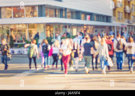 People rush on the street. Blurred crowd of different people are walking in the city. Defocused background of city life. Evening with lights. Stock Photo