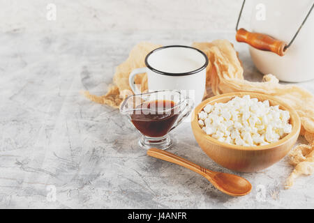 Granulated cottage curd in wooden bowl and mug of milk on light background Stock Photo