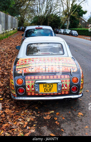 Nissan Figaro car, customised with prints from Lizzie Montgomery, reflecting the brown autumn leaves in which it's parked Stock Photo