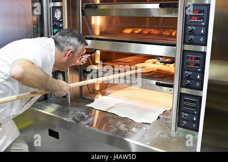 Baker bakes bread in the oven Stock Photo