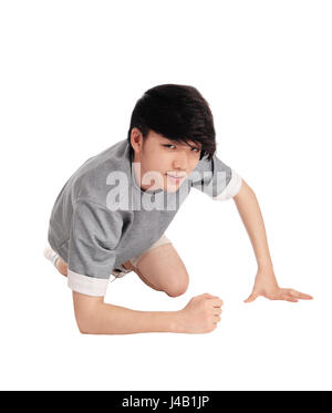 A good looking Asian teenager in a gray t-shirt kneeling on the floor in the studio in shorts, isolated for white background. Stock Photo