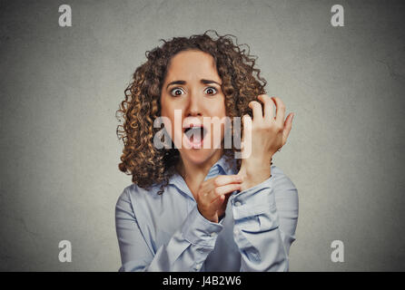 Reality check gesture. Portrait surprised woman pinching her arm skin, is this a dream, for real did it happen isolated grey wall background. Human em Stock Photo