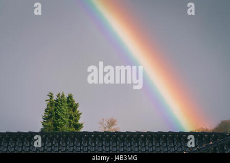 Colorful rainbow over a roof on house in the city just after the rain Stock Photo