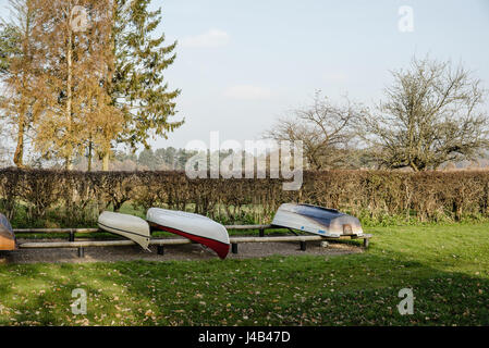 Boats on a row on land in autumn in a park with grass and trees near a lake. Stock Photo