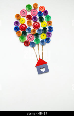 Creative concept photo of a house with air balloons made of paper on white background. Stock Photo
