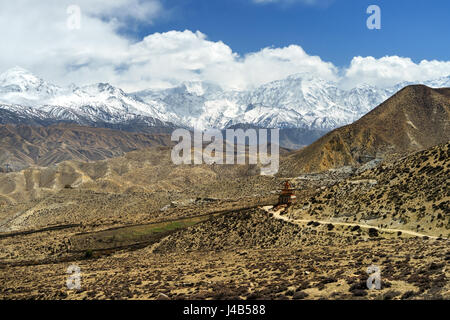 Mesmerizing landscape near Ghiling, Upper Mustang region, Nepal. Trekkers can be seen on the road leading to the chorten. Stock Photo