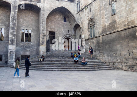 People sitting the steps leading to the Saló del Tinell and the Chapel of St. Agatha at Placa del Rei, Barcelona, Spain. Stock Photo