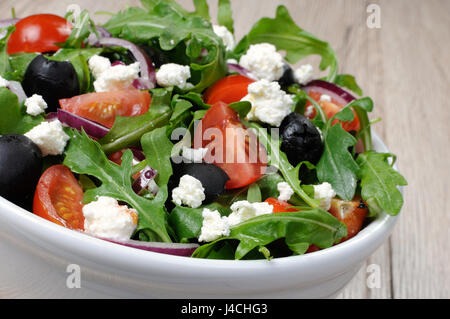 Variation of Greek salad with arugula, cherry slices, feta and olives Stock Photo