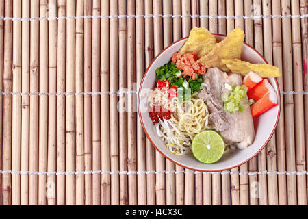 Japanese noodle (ramen) in spicy soup as 'tom yam ' topped steamed streaky pork,wonton,green lemon,crab stick,dried shrimp,bean sprouts,roast nut and  Stock Photo