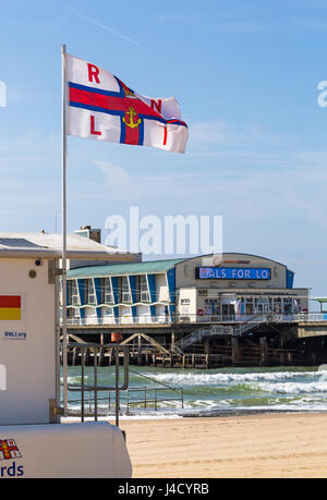 RNLI flag flying at RNLI Lifeguard station on Bournemouth beach by Bournemouth Pier in May Stock Photo