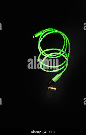 Green lightning to usb cable and sd memory card in a dark environment set, flat lay and black background Stock Photo