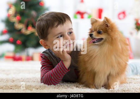 Little kid boy with dog lying on the floor in festival room Stock Photo