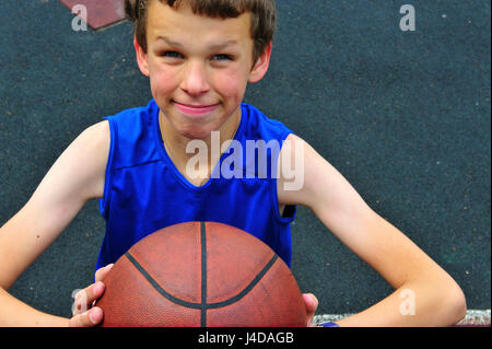 Little basketball player preparing for throwing ball on basketball court Stock Photo