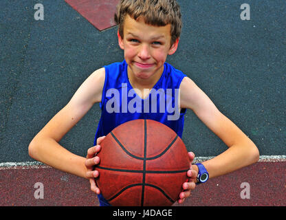 Little basketball player preparing for throwing ball on basketball court Stock Photo