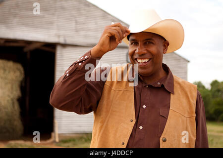 African American cowboy smiling and tipping his hat Stock Photo
