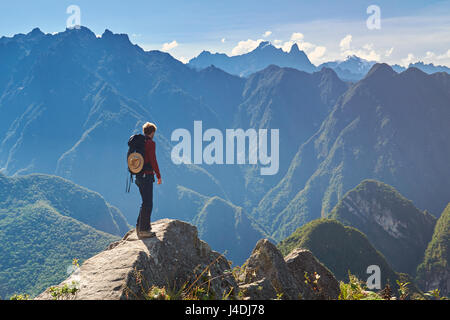 Man walking on mountain peak in summer sunny bright day Stock Photo