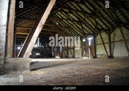 Empty rural barn with wooden supports and remains of hay on the floor Stock Photo