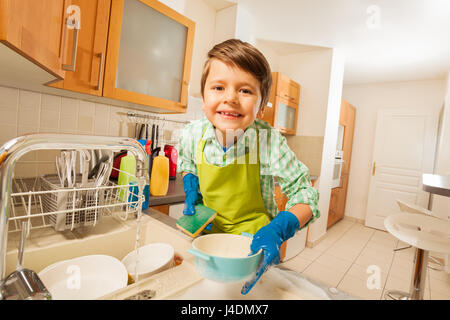 Cute kid boy doing the dishes in rubber gloves Stock Photo