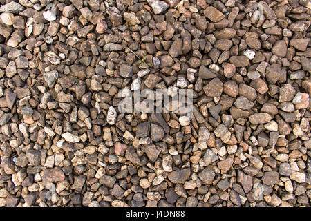 Bulk of granite rubble on the railway. Gray and brown dirty old crushed stone texture or background. A spring cloudy day. Gloomy mood. Stock Photo