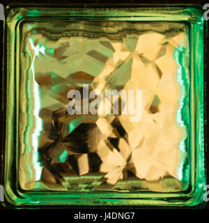 Green square glass block close up. Building material. Element of the wall. Refraction of light inside a glass object creates an interesting effect. Stock Photo