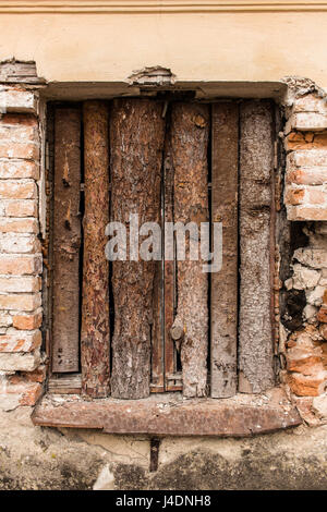 The window of the ruined house closed with wooden boards. The plaster on the wall around the window is crumbled. Masonry is partially destroyed. Very  Stock Photo