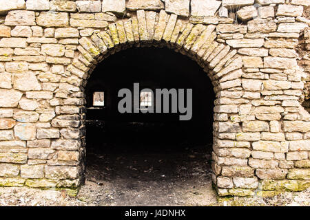 Opening in the wall made in the form of an arch. Limestone carpentry walls.  A window with a lattice in the depths. Stock Photo