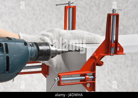 hands of carpenter drills a hole for furniture screw Stock Photo