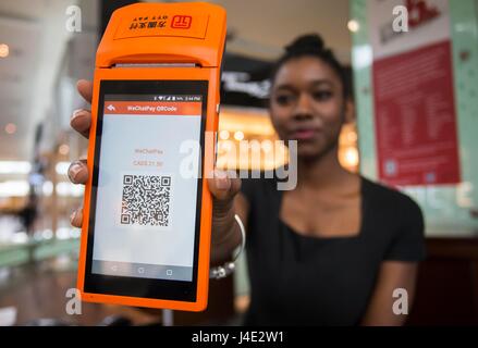 (170512) -- TORONTO, May 12, 2017 (Xinhua) -- A staff member shows a WeChat Pay QR code at Yorkdale Shopping Centre in Toronto, Canada, May 11, 2017. Canada's shopping mall Yorkdale Shopping Centre started accepting China's WeChat Pay from May 2017. Tourism Toronto and OTT Financial Group have introduced the Chinese mobile payment service, WeChat Pay, into local tourism to boost travel and shopping consumption by Chinese travelers.(Xinhua/Zou Zheng)(gj) Stock Photo