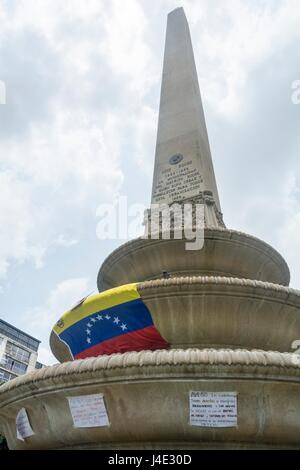 Young people place a flag of Venezuela in the Obelisk of the France square of Altamira.Under the motto 'Our Shield is the Constitution', or also called the 'March of the Shields', demonstrators began to concentrate in different parts of the city to reach Supreme Court of Justice (TSJ). Caracas, May,10,2017 Stock Photo