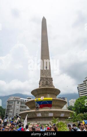 Young people place a flag of Venezuela in the Obelisk of the France square of Altamira.Under the motto 'Our Shield is the Constitution', or also called the 'March of the Shields', demonstrators began to concentrate in different parts of the city to reach Supreme Court of Justice (TSJ). Caracas, May,10,2017 Stock Photo