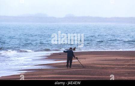 Exmouth, UK. 12th May, 2017. UK Weather. A cool and misty start on Exmouth beach - a man searches for buried treasure with a metal detector. Credit: South West Photos/Alamy Live News Stock Photo