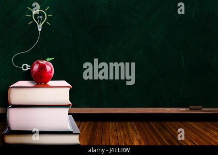 Education concept with apple on stack of books on blackboard background. Lightbulb signifies power of ideas and knowledge. Copy space on chalk board. Stock Photo