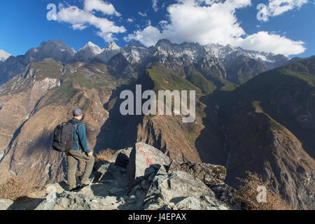 Man hiking in Tiger Leaping Gorge, UNESCO, with Jade Dragon Snow Mountain (Yulong Xueshan), Yunnan, China Stock Photo