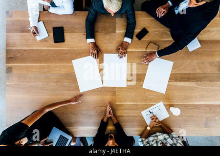 Group of people placing blank placards on table. Top view of business people having a meeting. Stock Photo